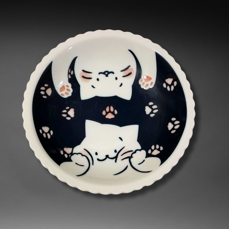 An overhead view of the full 21 cm scalloped plate. The deep blue interior features two white cats surrounded by pink and brown paw prints.