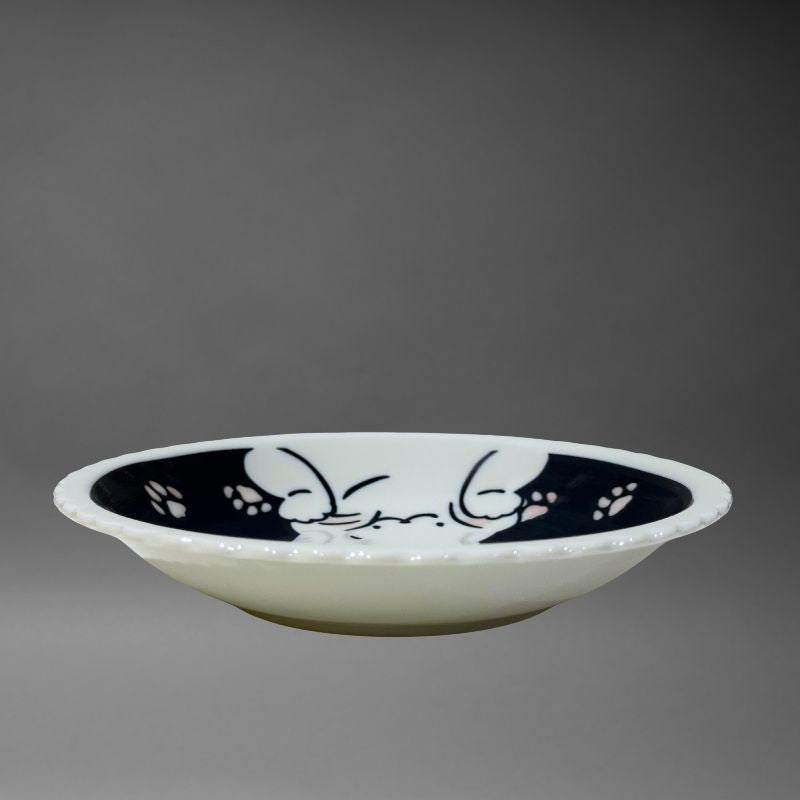 A studio side view of the shallow ceramic bowl, highlighting the deep blue interior design and the white scalloped edge.
