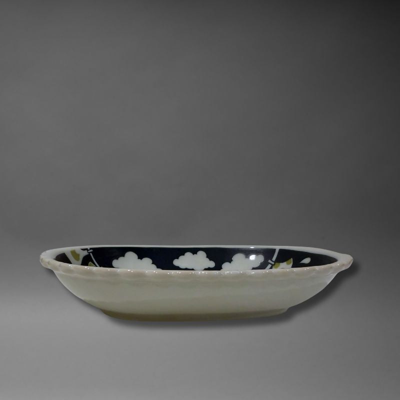 A low-angle side view of the oval serving bowl, highlighting its depth and the white, scalloped 'biscuit' rim and exterior. The interior design is partially visible.