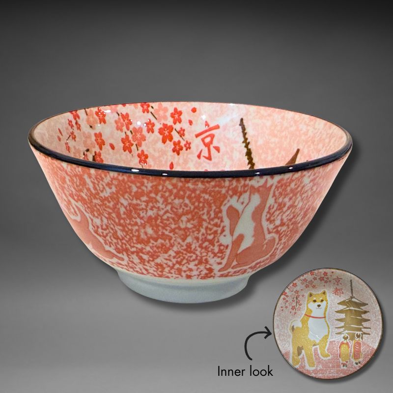 An overhead studio view of the small 13 cm ceramic rice bowl. The interior features a yellow/brown Shiba dog standing in front of a pagoda and pink cherry blossoms, with the Japanese text '京都' (Kyoto) visible against a speckled background.