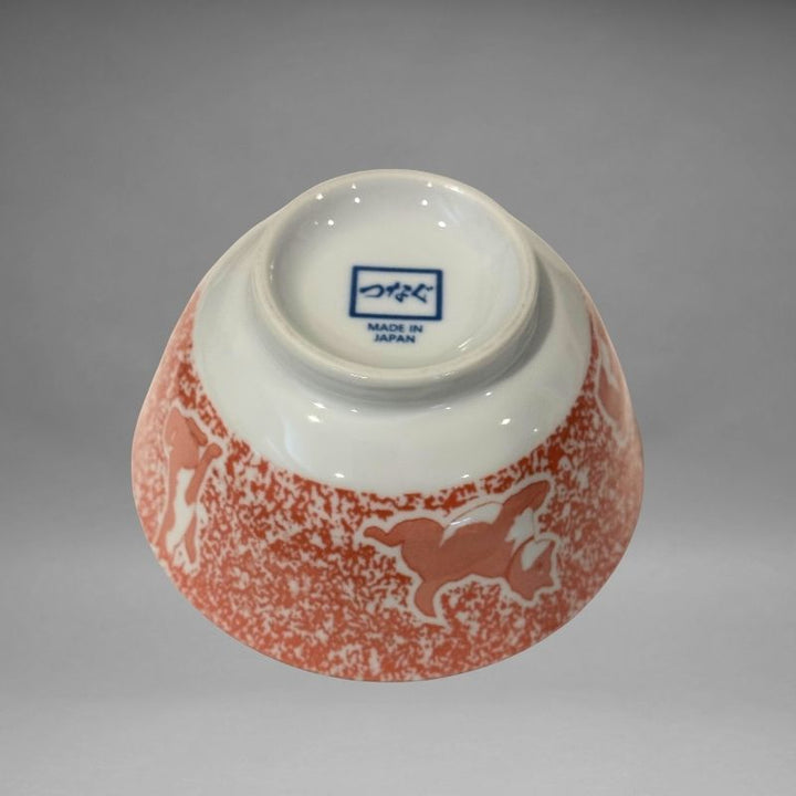 An inverted, bottom-up view of the small ceramic rice bowl, showing the white base and the blue 'つなぐ MADE IN JAPAN' mark stamped in the centre.