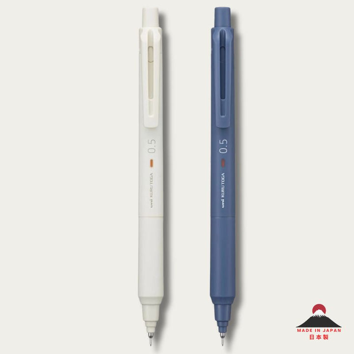 Two 0.5 UNI-BALL KURU TOGA mechanical pencils, one ivory white and one in Iron blue, shown vertically side-by-side on a light gray background with a small Japanese &