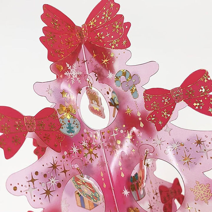 Close-up of clear pink tree panels with red foil bows and dangling ornament charms on a Sanrio Hello Kitty Christmas card