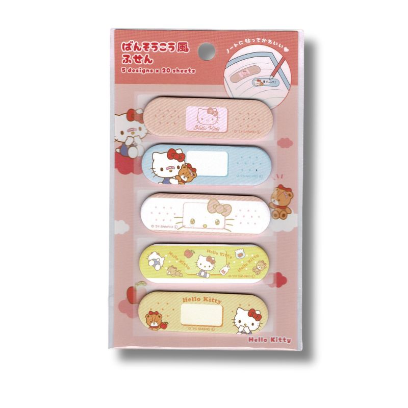 Sanrio Hello Kitty bandage-style sticky notes set, Japanese Exclusive Edition. Five pastel bandage-shaped memo designs featuring Hello Kitty and teddy motifs in pink, blue, white, yellow and beige. Packaging shown on a white background.