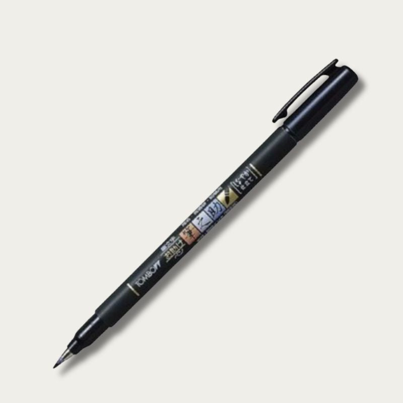 A clear, high-resolution shot of an uncapped Tombow Fudenosuke Soft Tip calligraphy pen in black, highlighting the flexible elastomer brush nib and professional-grade barrel design.