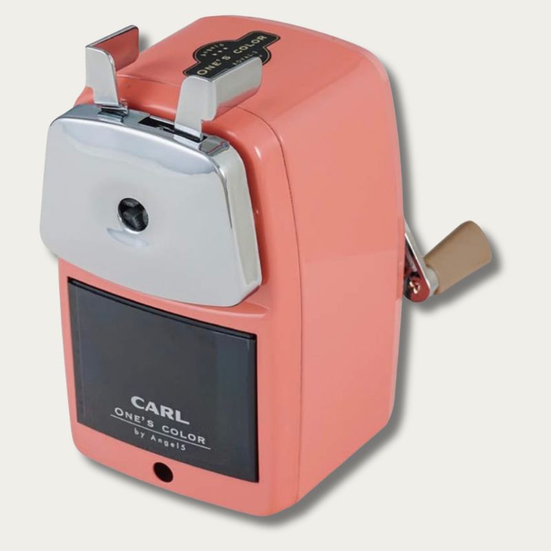 Pink CARL Angel 5 Royal 3 manual desktop pencil sharpener featuring a chrome pencil entry, metal clamp ears, and a front shavings drawer against a plain background.