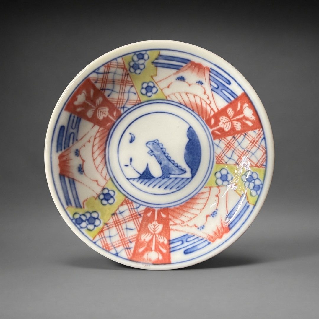 Edokko Dinosaur Asahiryu mame plate 9cm, a spiky-backed dinosaur in a blue medallion with red Mt Fuji and plum blossom panels, Mino ware