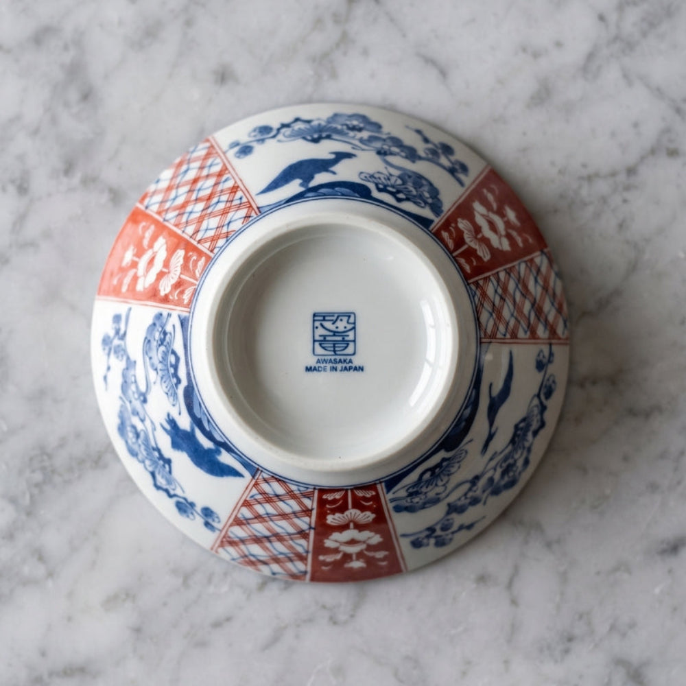 Underside of the Edokko Dinosaur ramen bowl showing blue dinosaurs among pine trees, red Ko-Imari panels and the Awasaka Made in Japan back stamp