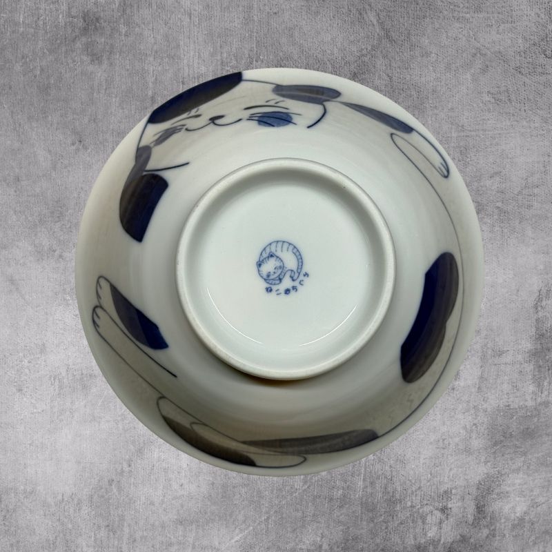 An inverted, bottom-up view of the ramen bowl. The exterior cat design is visible, and the foot of the bowl clearly shows the Japanese mark of the cat maker.
