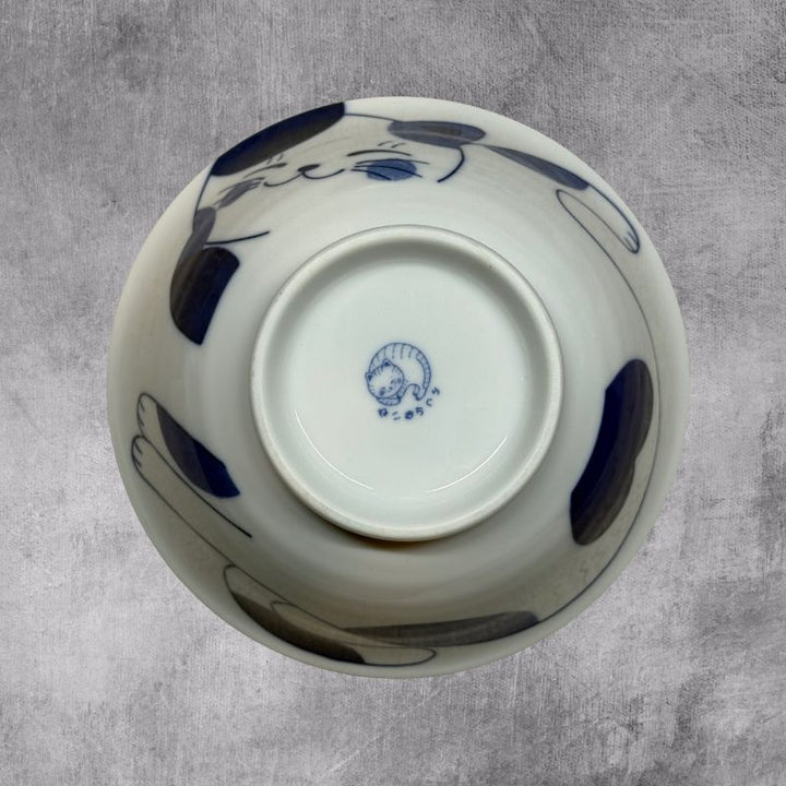 An inverted, bottom-up view of the ramen bowl. The exterior cat design is visible, and the foot of the bowl clearly shows the Japanese mark of the cat maker.