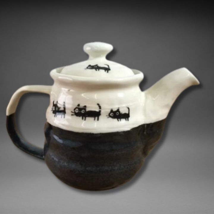 Side view of Mino-yaki teapot featuring playful black cat patterns on ivory and black glaze.