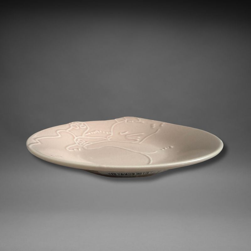 Side angle of Sakura Pink Mino-yaki Nyanmonite plate highlighting curved edge and gentle relief of curled-up cat motif.