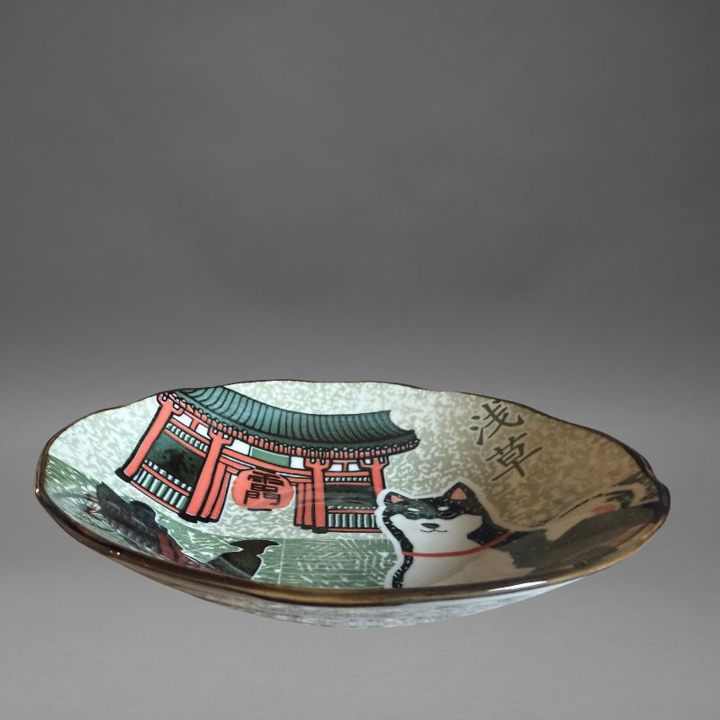 A low-angle studio view of the deep serving plate, highlighting the full design: the Shiba dog, the Kaminarimon Gate, and a silhouette of a rickshaw on the speckled grey and green interior.