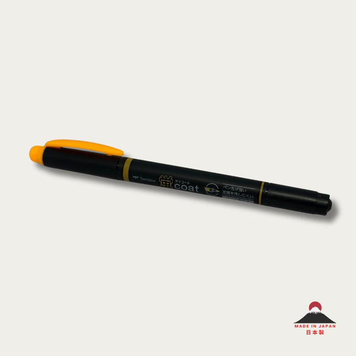 A high-resolution product shot of a single Tombow Kei Coat highlighter in golden yellow. The black pen body features the "蛍coat" logo and icons indicating its reinforced nib and refillable ink system.