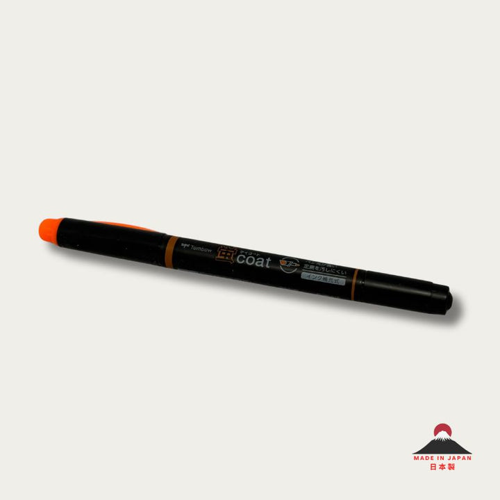 A high-resolution product shot of a single Tombow Kei Coat highlighter in orange. The black pen body features the "蛍coat" logo and icons indicating its reinforced nib and refillable ink system.